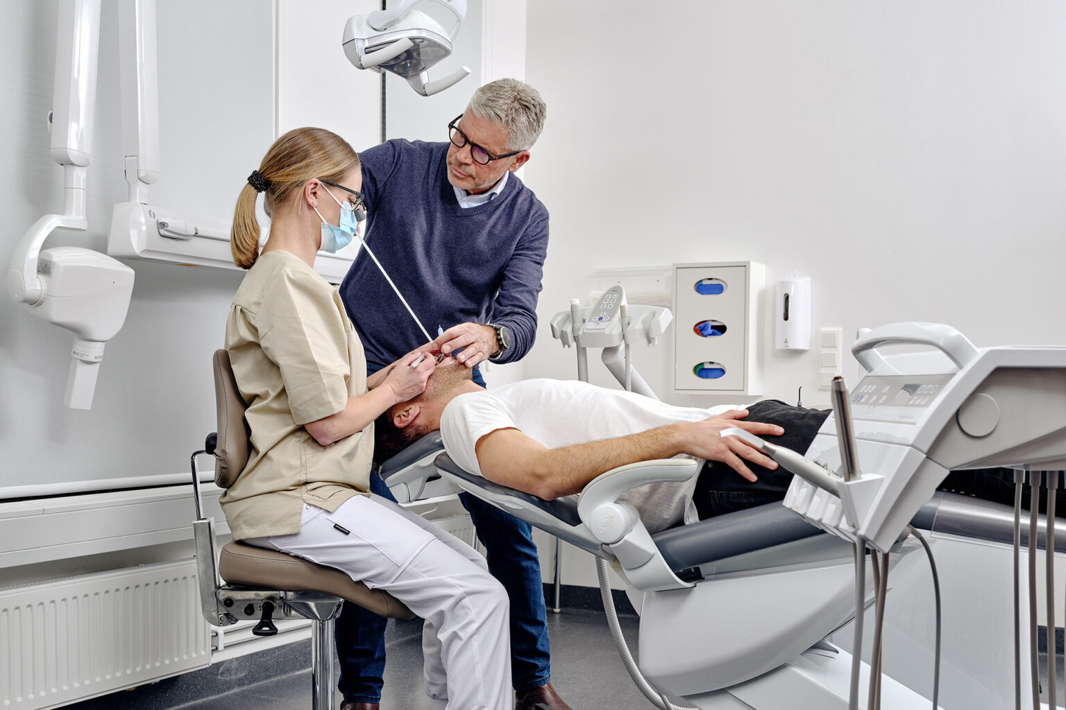 A man is assisting a woman in finding the right ergonomic setup. The woman is wearing Optergo Flip-up Loupes
